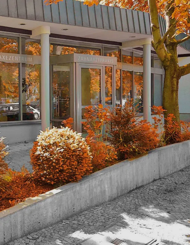 Zahnarztpraxis im Herbst, modernes Gebäude mit Herbstlaub.
