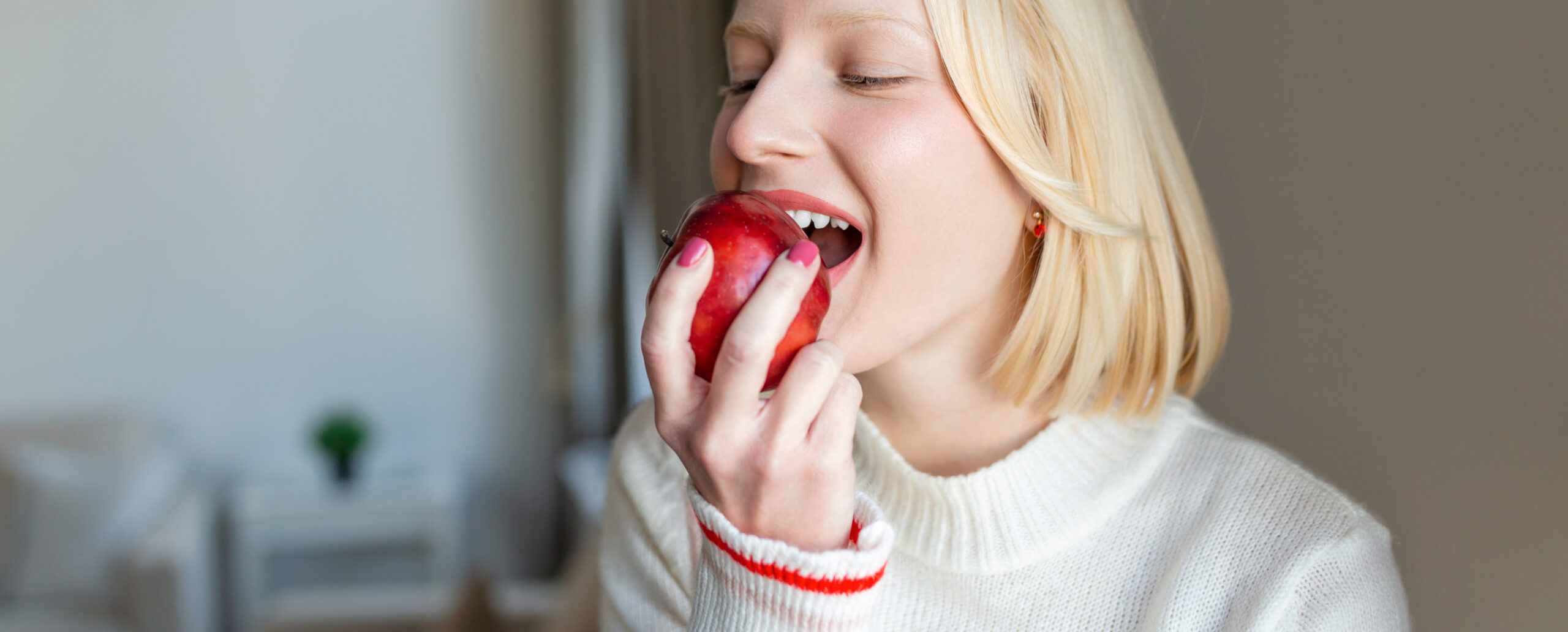 Frau beißt in Apfel - gesunde Zähne und Ernährung.
