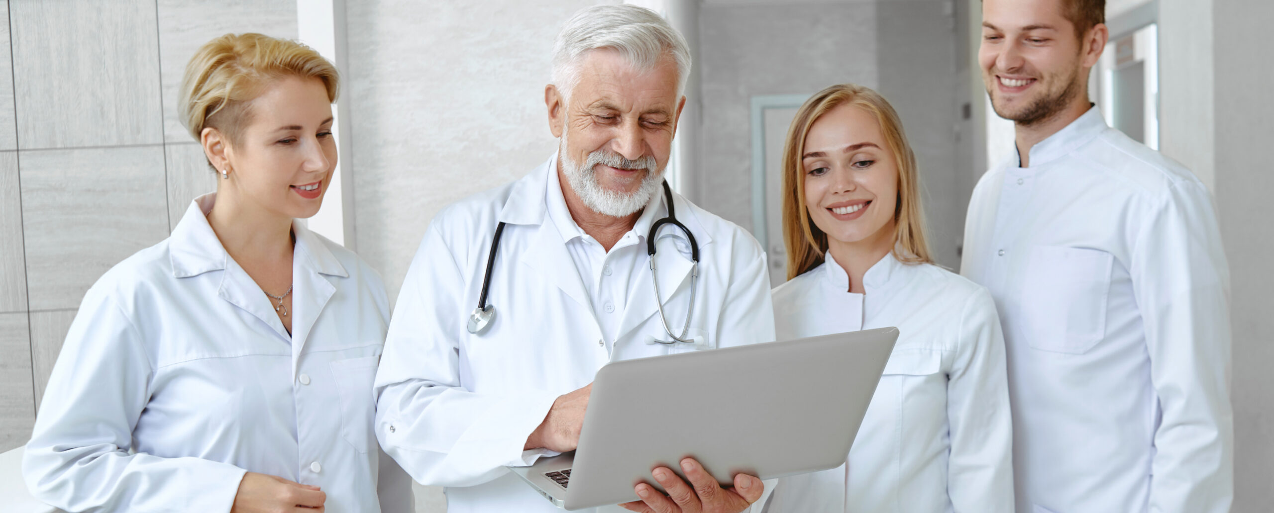 Zahnärzteteam bespricht Patientenbehandlung am Laptop in moderner Praxis.