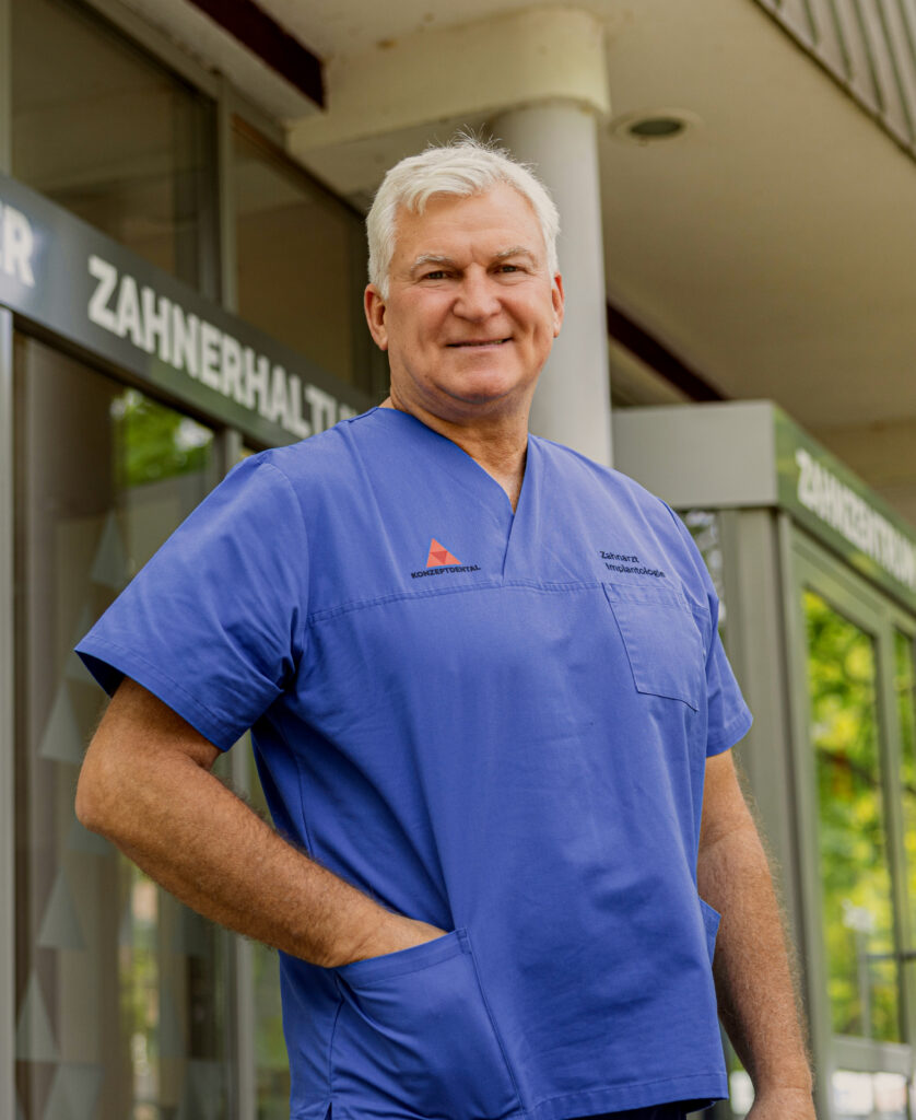 Zahnarzt in blauer Uniform vor Praxisgebäude.