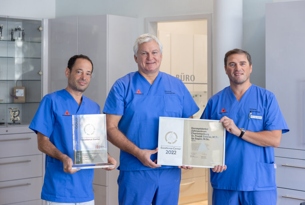 Zahnarztteam in blauer Uniform mit Auszeichnungen im Bereich Zahnmedizin.
