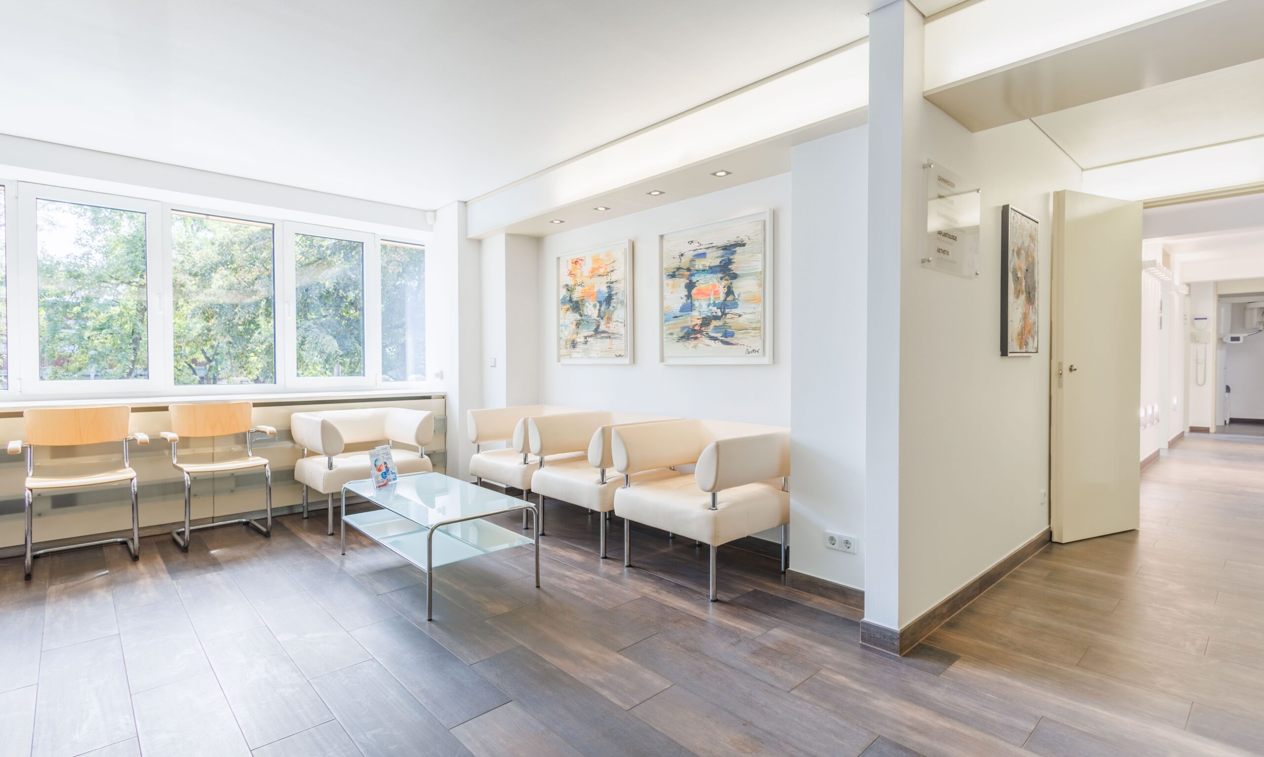 Moderne Zahnarztpraxis-Wartezimmer mit heller Einrichtung und bequemen Sitzgelegenheiten.