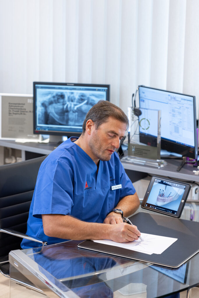 Zahnarzt bei der Diagnose mit Röntgenbild auf Monitor im modernen Praxisbüro.