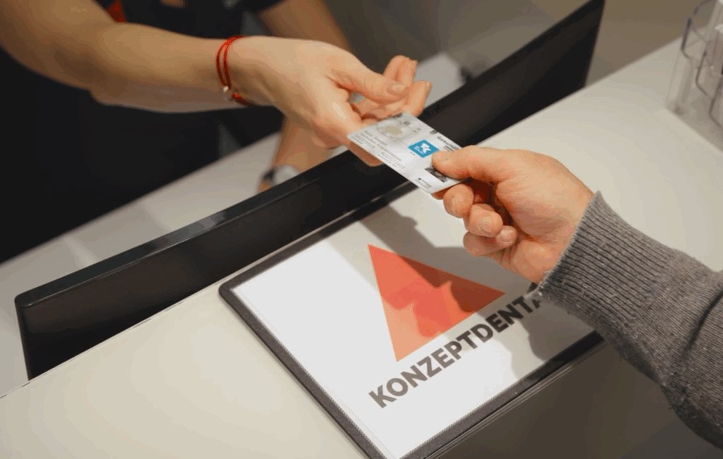 Patient überreicht Krankenkarte beim Zahnarztempfang.