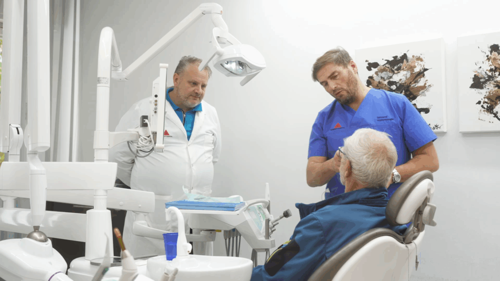 Zahnärzte beraten Patient im Behandlungsraum.