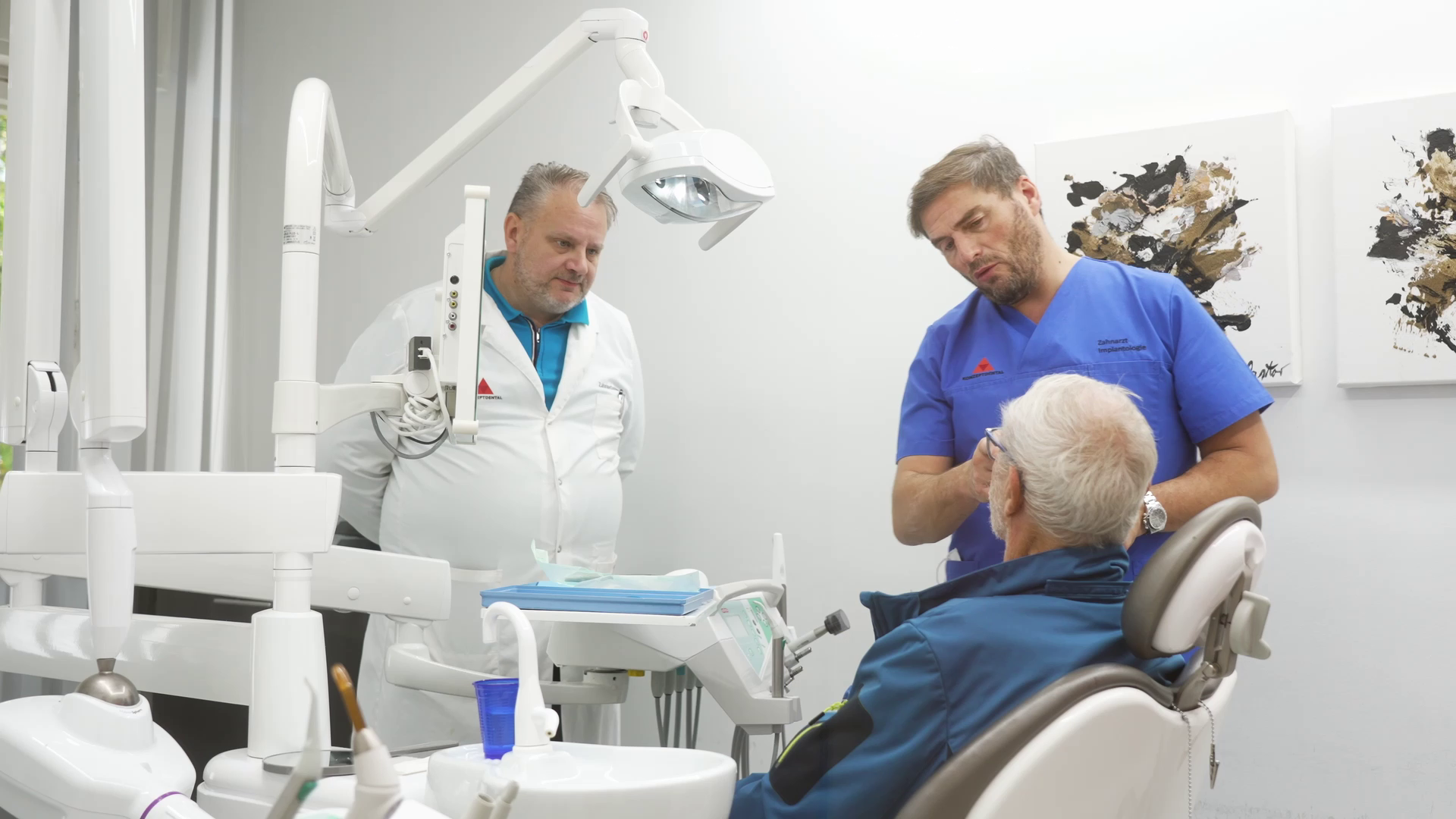 Zahnärzte beraten Patient im Behandlungsraum.